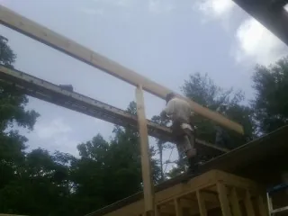 Carpenter setting a ridge beam over a new addition frame — Ice Dam Removal by Roofing Brothers in Arvin