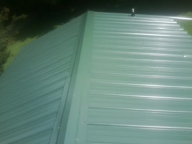 New green metal panels meeting at the ridge of a roof — Flat Roof Repair work by our crew in Arvin