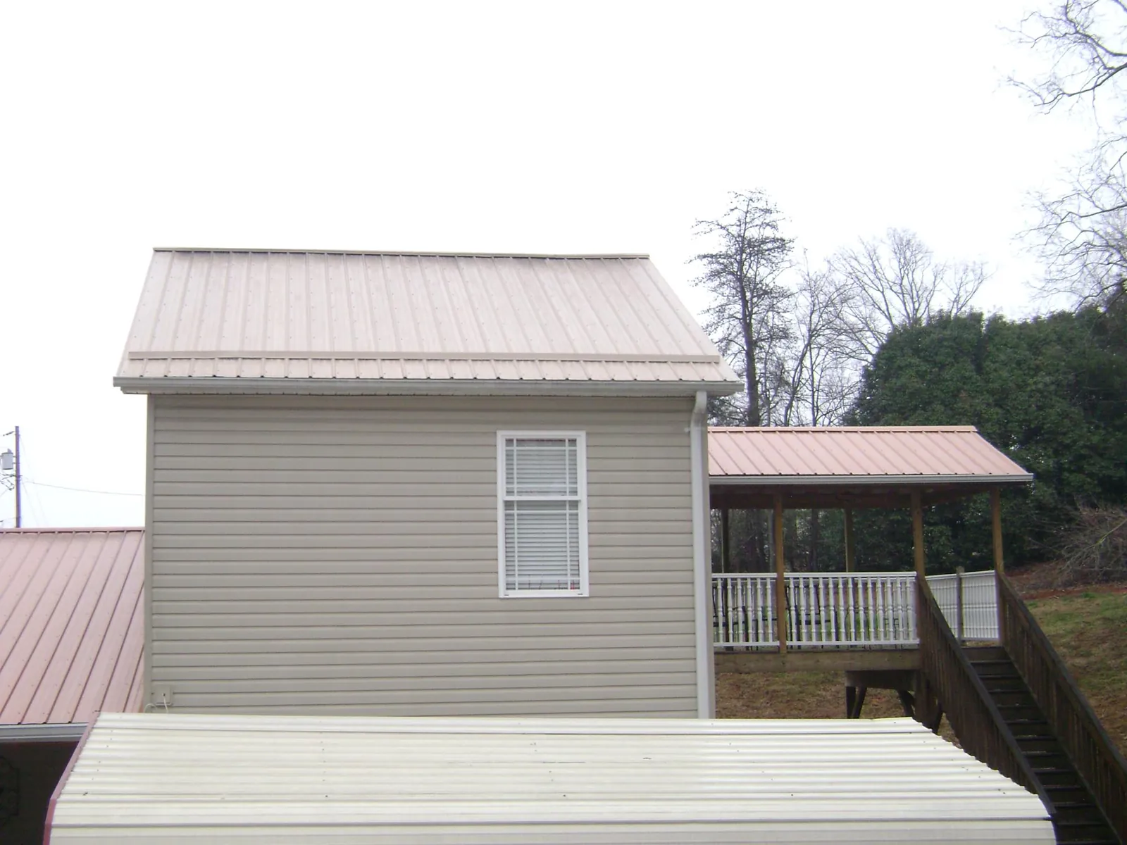 Tan metal roofs on a two story addition and attached porch, from a Roof Replacement job in Arvin